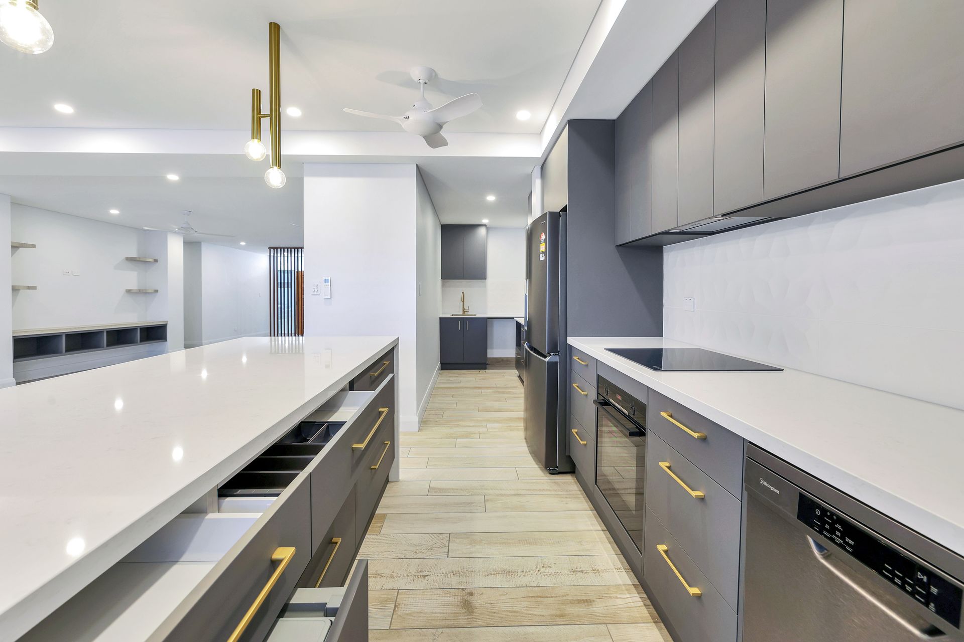 Modern kitchen with gray cabinets, white countertops, and a long island.