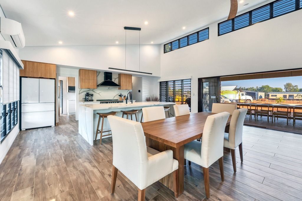 Spacious open-plan kitchen and dining area with wooden table, white chairs, and large sliding doors.