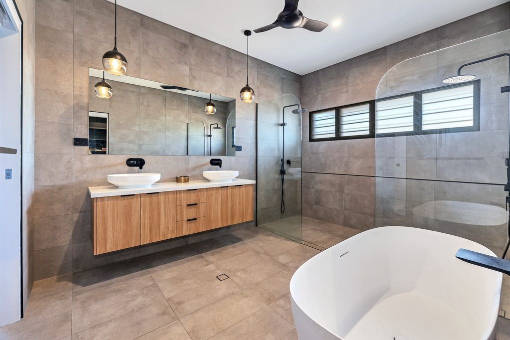 Modern bathroom with floating wood vanity, double sinks, freestanding tub, and large glass shower.