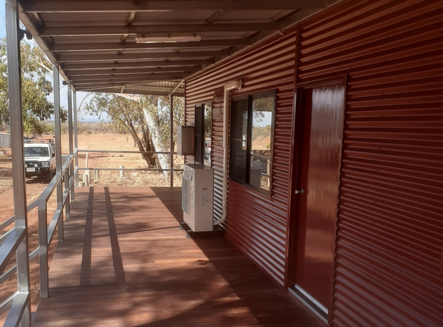 Red corrugated iron building with wooden deck and wheelchair ramp.