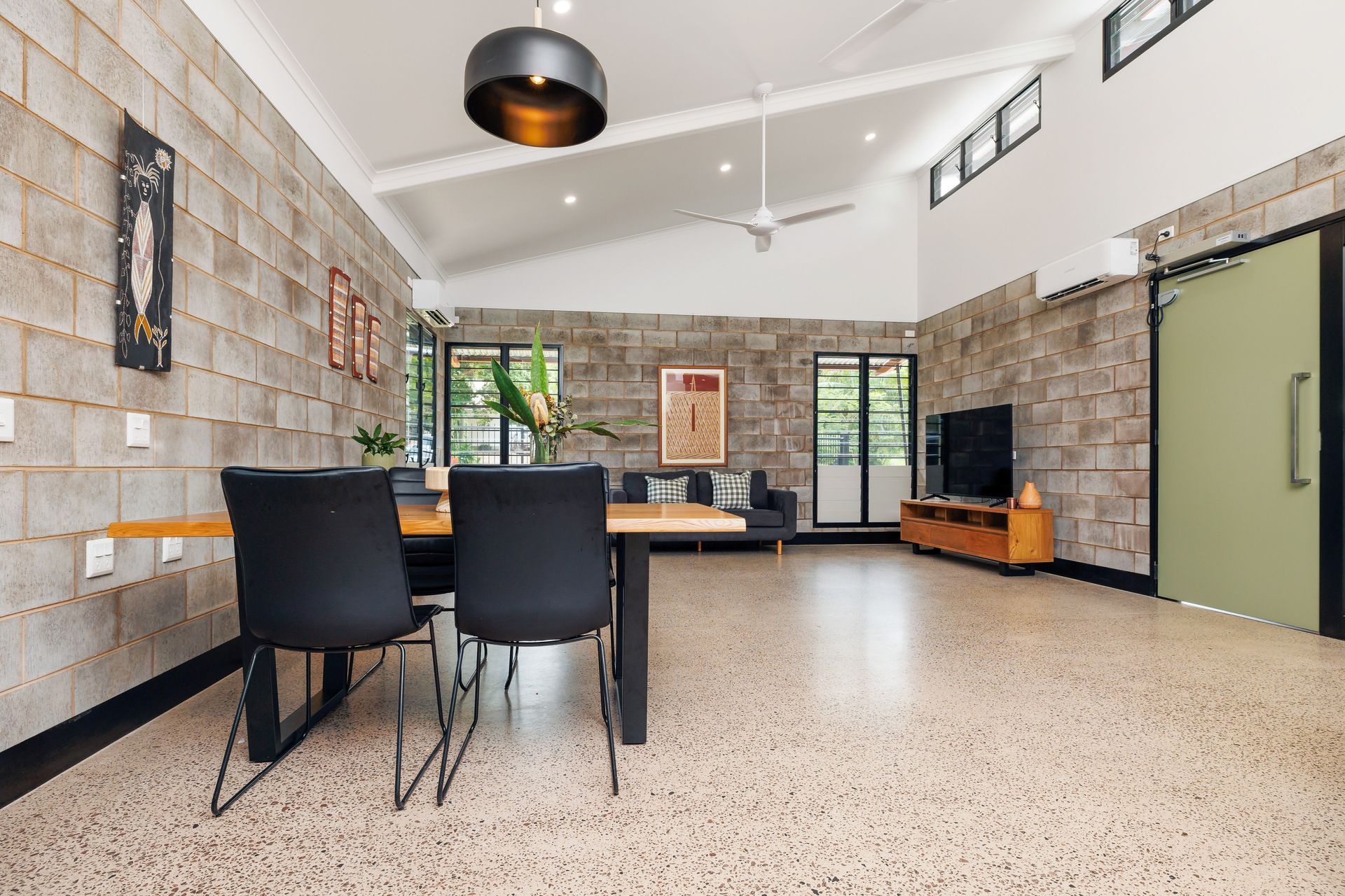 Dining area with concrete block walls, terrazzo floor, black chairs, and a black dining table.