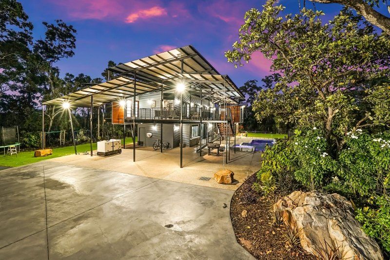 Two-story modern home with a large patio at dusk, with a pool in the back.
