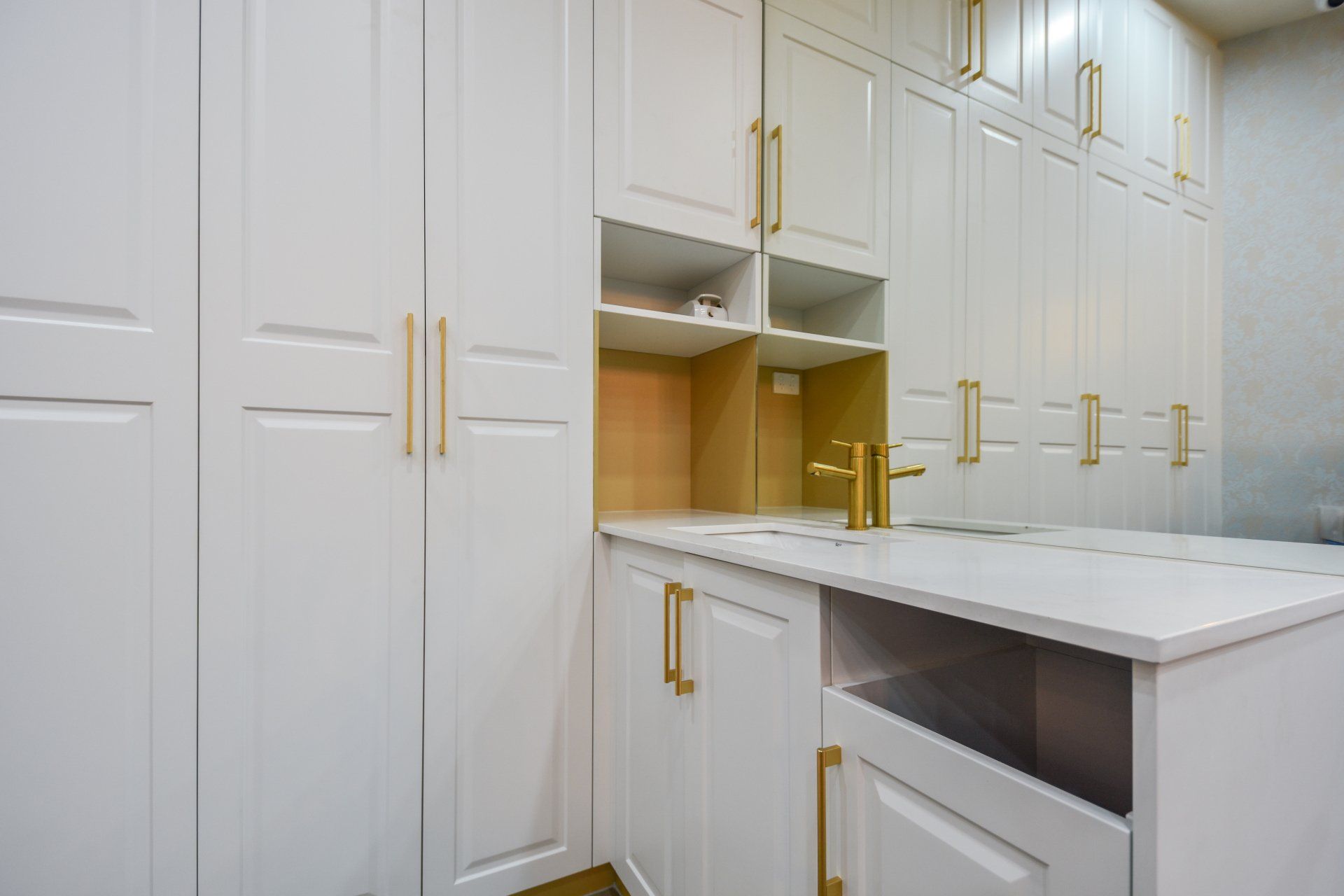 White walk-in closet with gold hardware and countertop.