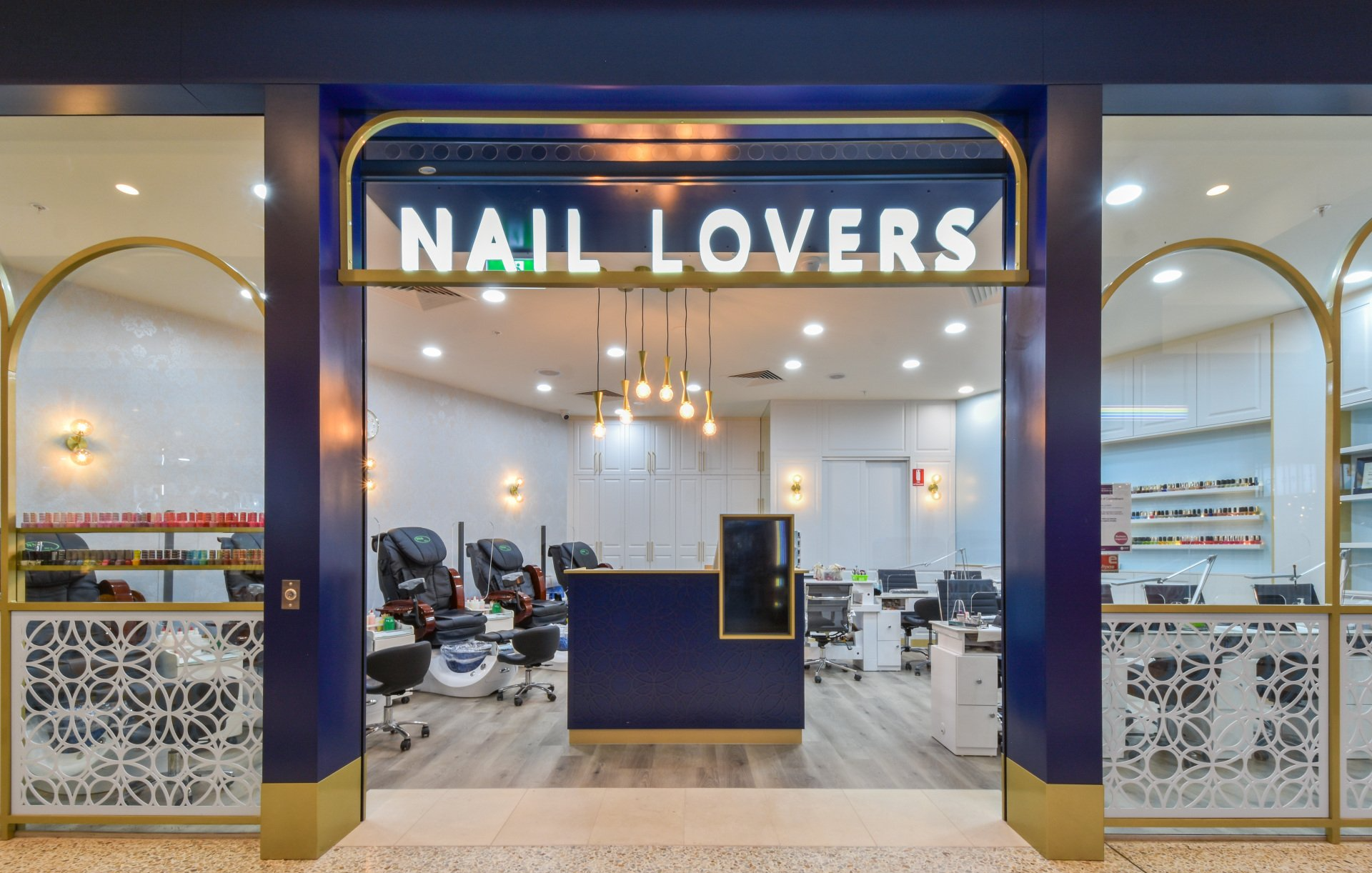 Nail Lovers salon entrance with navy and gold accents. Interior with nail stations and decor.