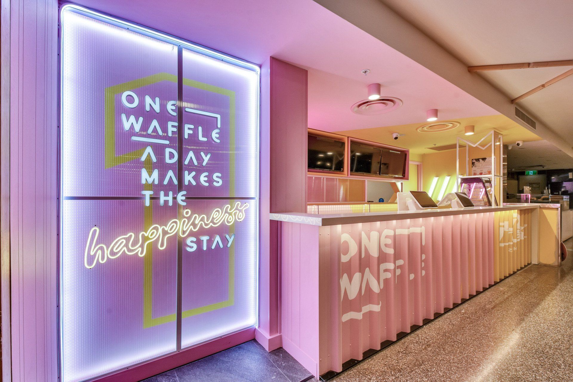 Pink and yellow waffle shop interior with a neon sign: 