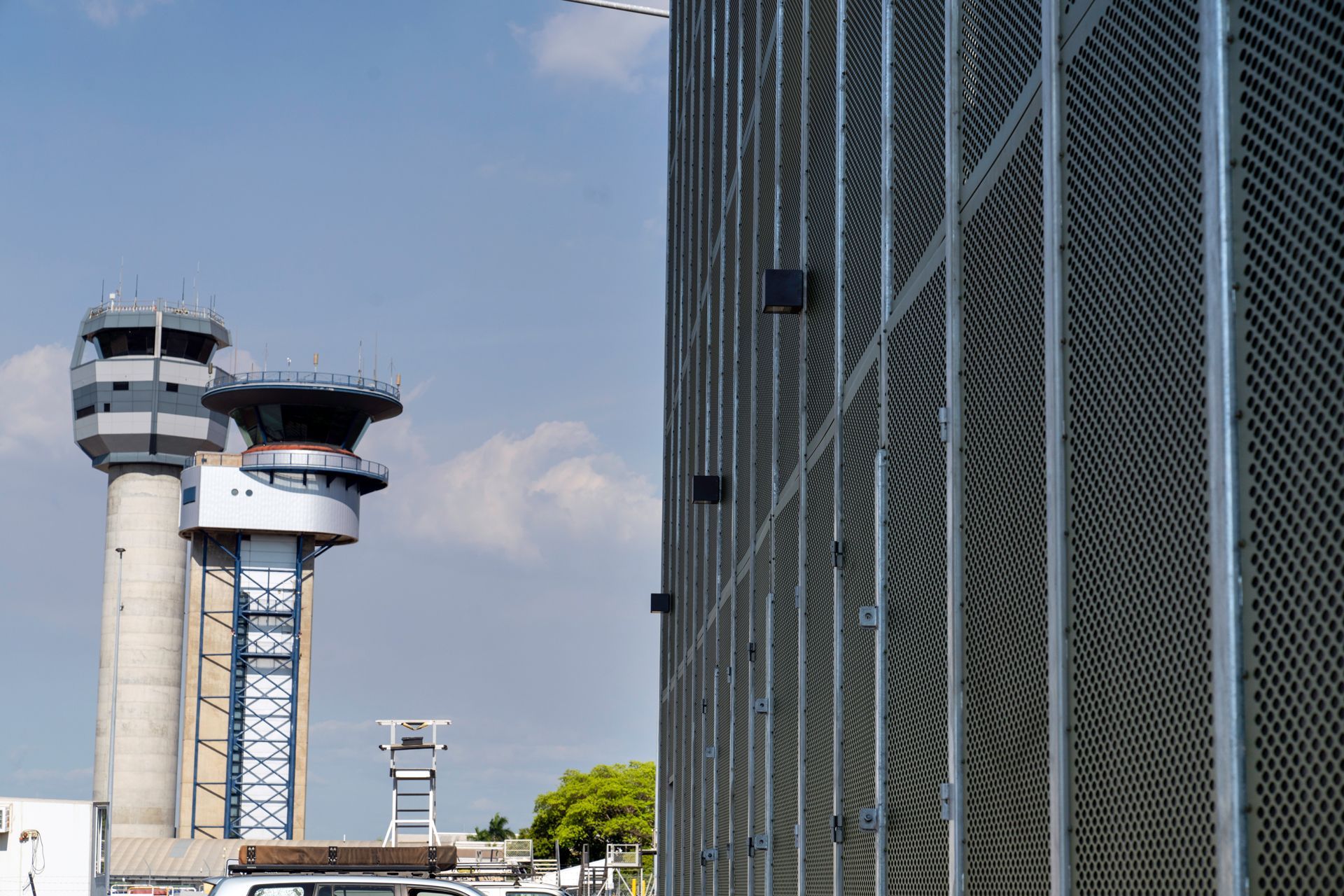 Airport control towers and a textured building exterior against a blue sky.