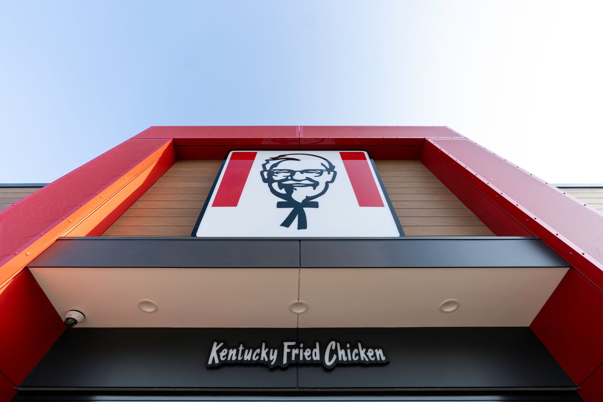 KFC restaurant exterior with a large sign featuring Colonel Sanders against a red and black background.