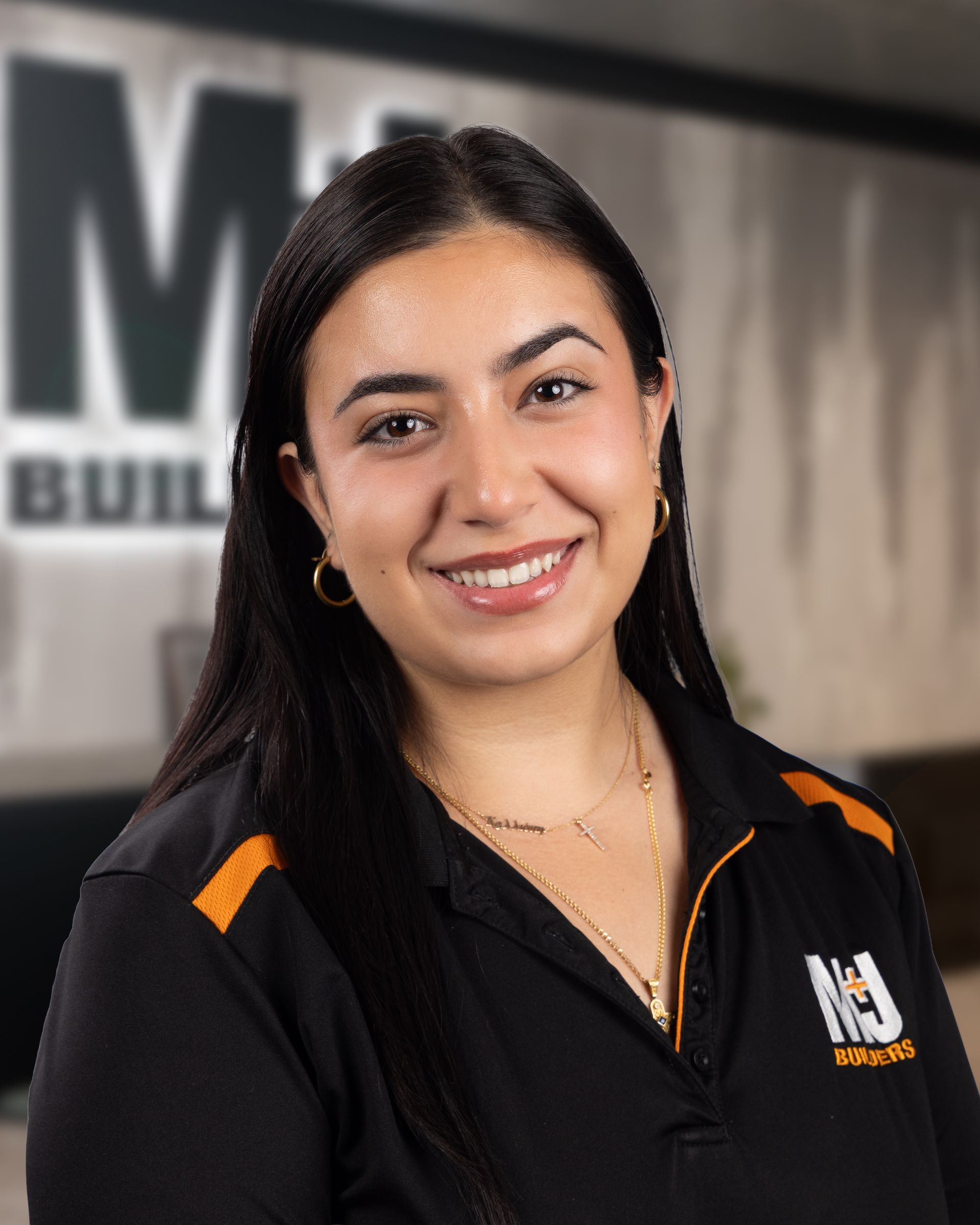 Woman with dark hair and purple highlights, smiling, wearing a black shirt with a company logo on a white background.