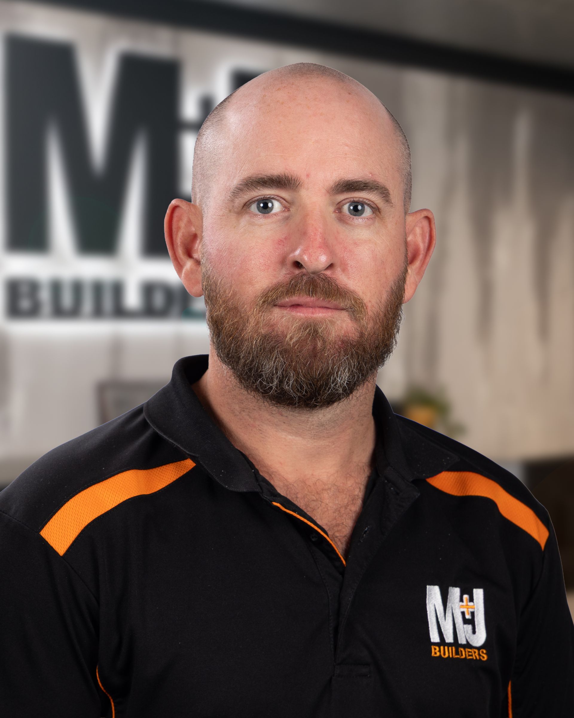 Bald man in orange work shirt smiles at the camera.