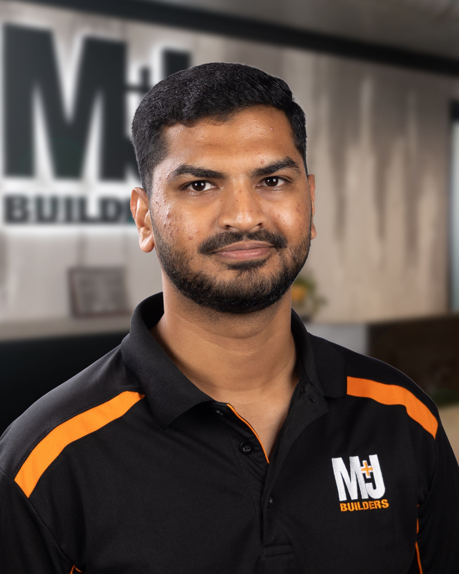 Man with glasses wearing black shirt with orange accents and logo