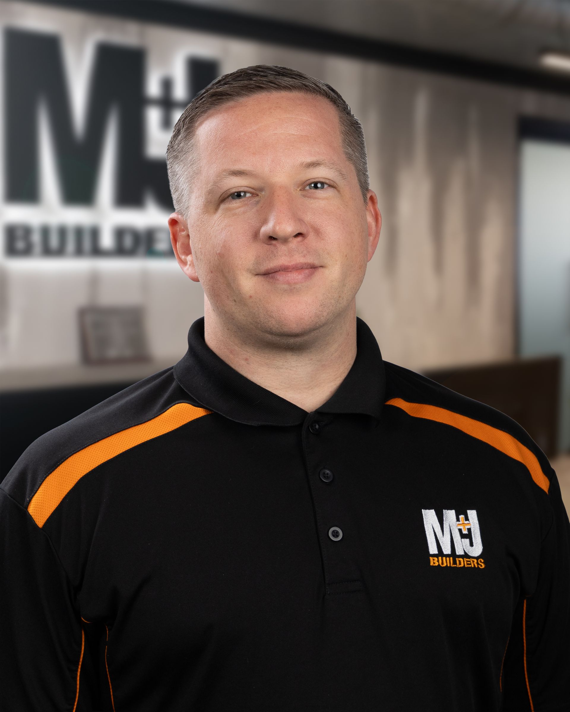 Man wearing a black polo shirt with orange accents and the text