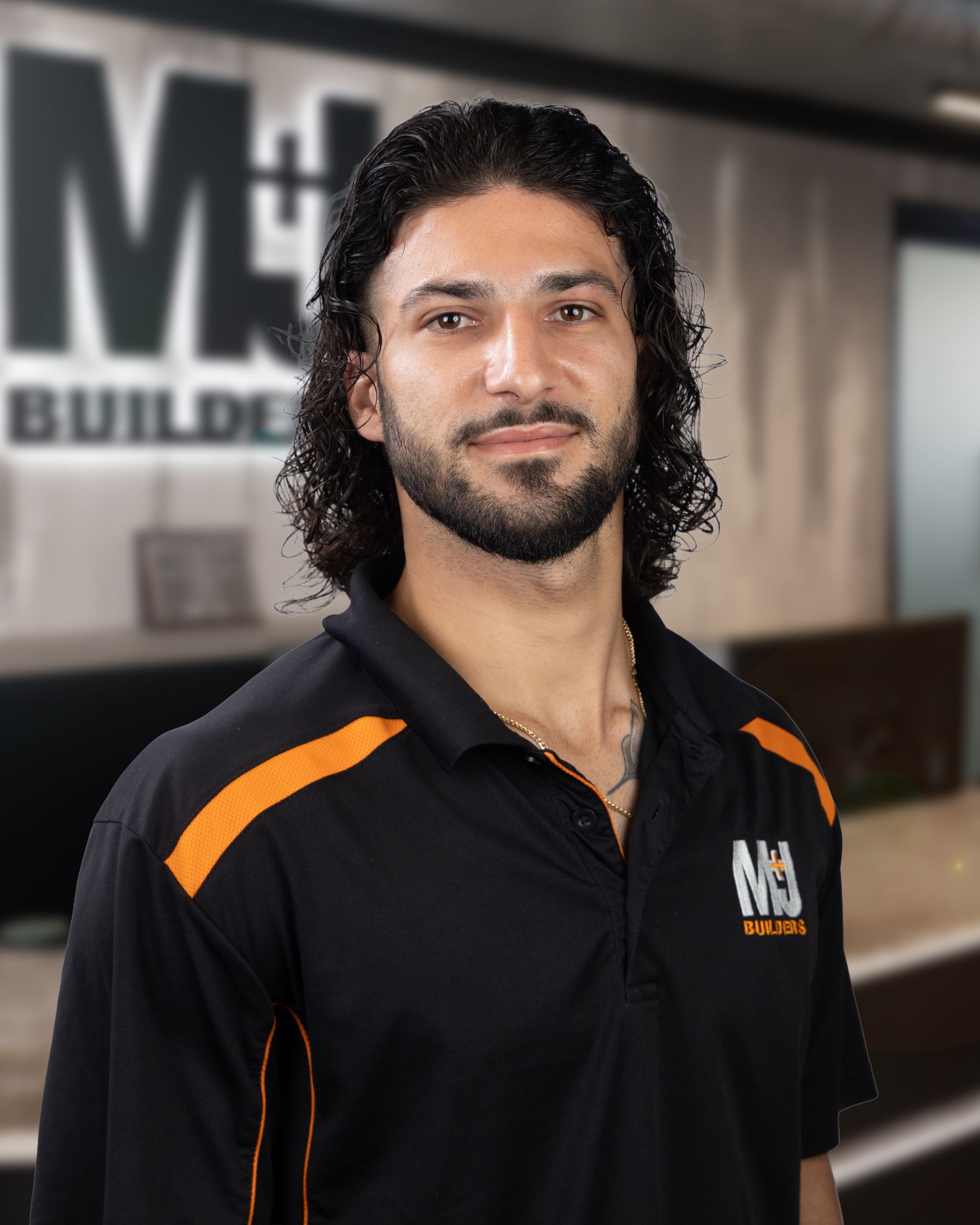Man with dark hair and beard, wearing a black polo shirt with orange accents.