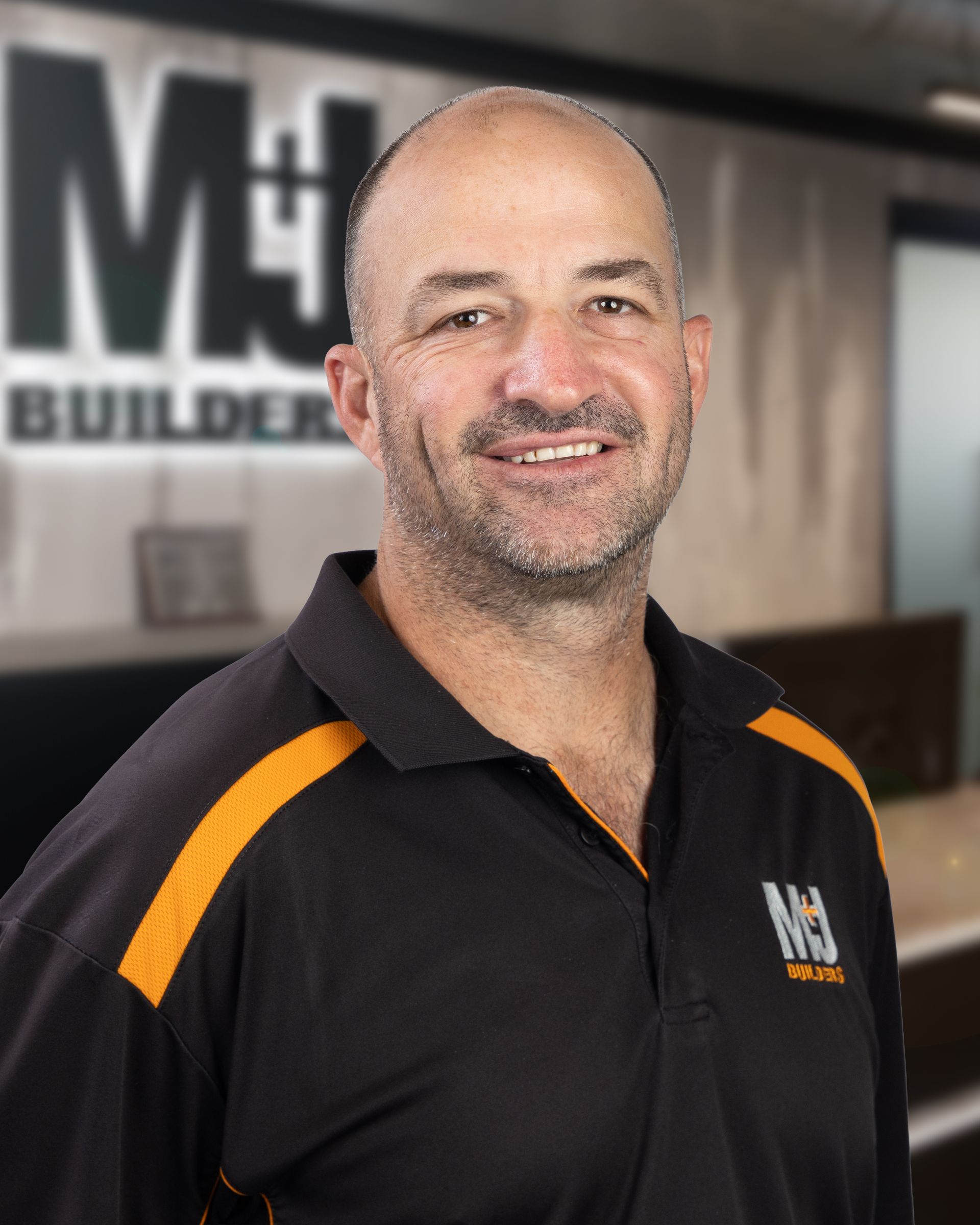 Man wearing black polo shirt with orange accents, smiling.