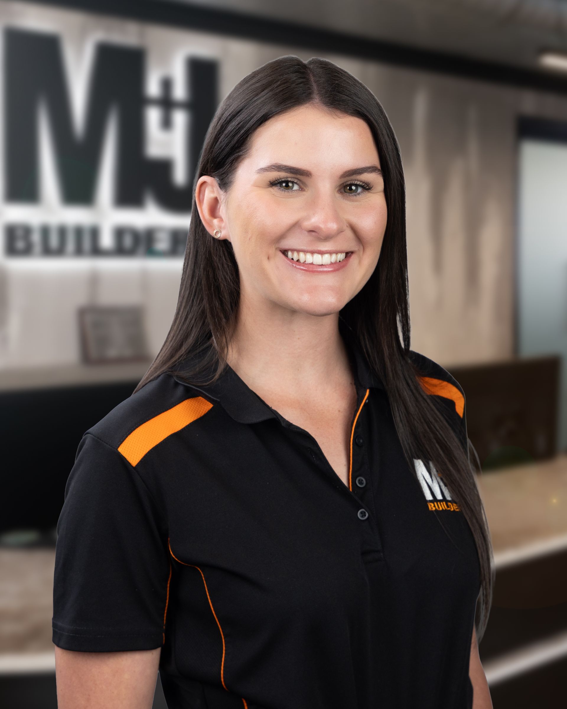 Woman with long dark hair smiles in black polo shirt with logo.
