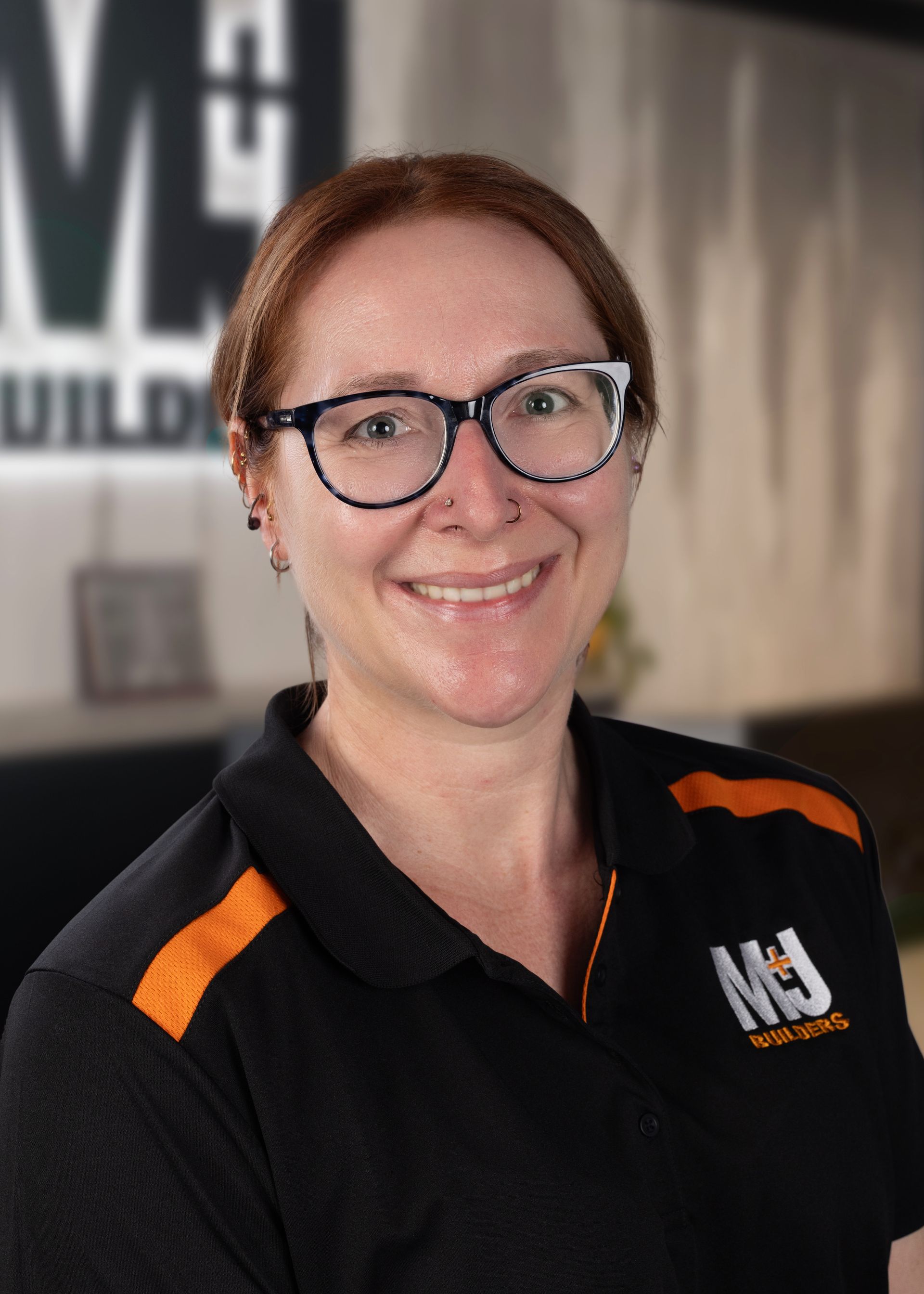 Woman with blonde hair, glasses, and a black shirt smiles at the camera.