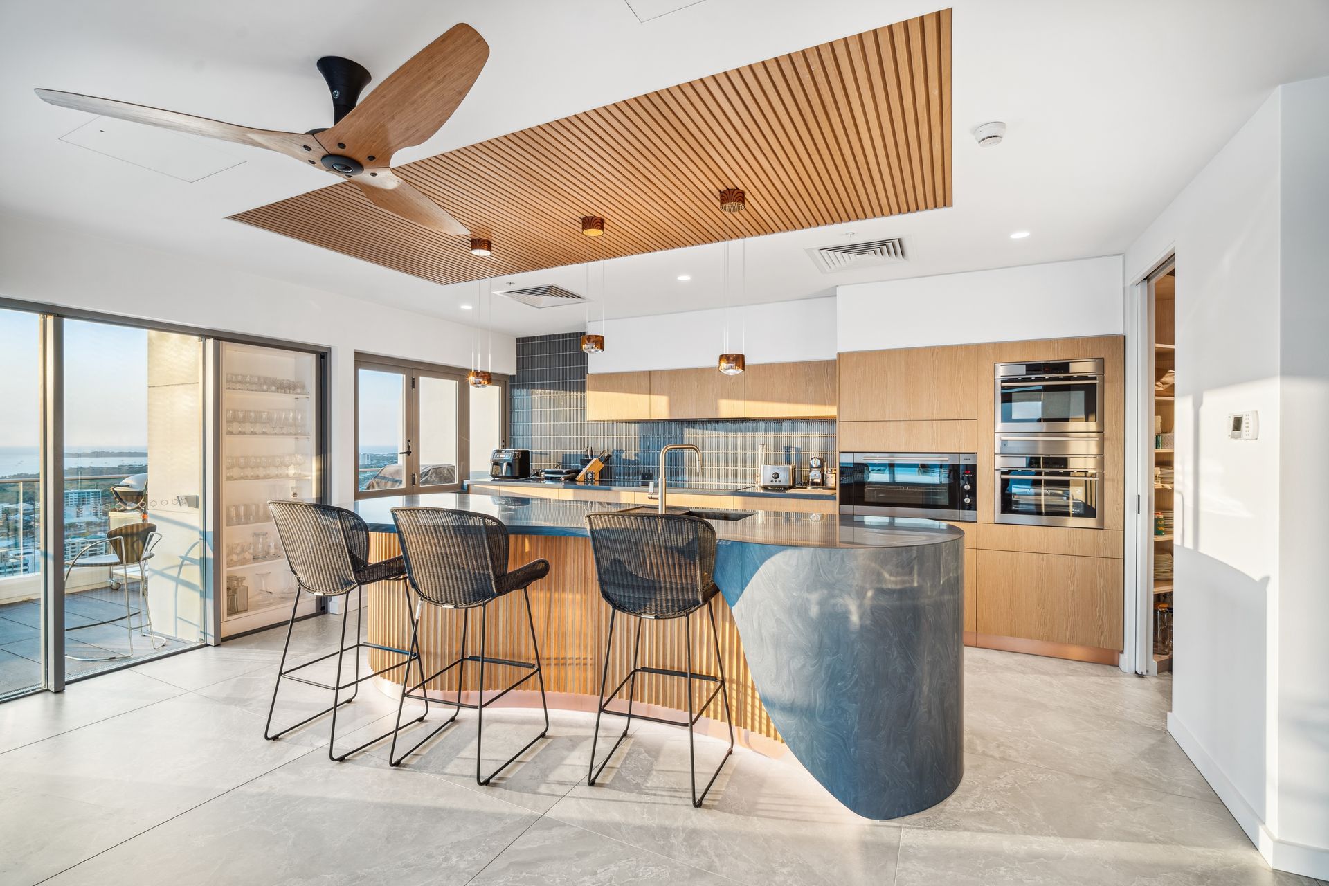 Modern kitchen with a wood ceiling, island, and bar stools.