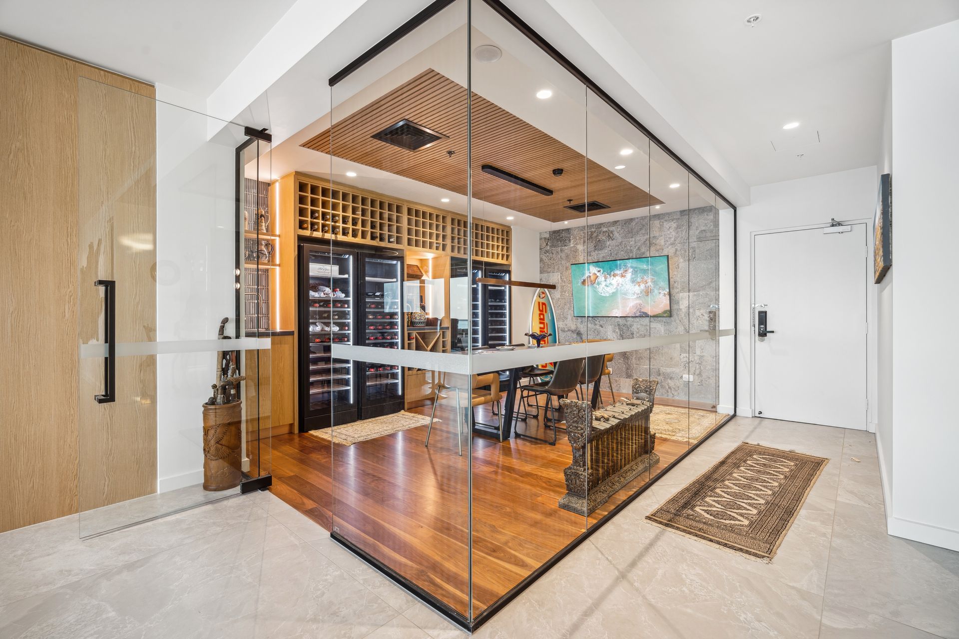 Modern wine cellar enclosed in glass, with wooden floors and a wall of wine storage.