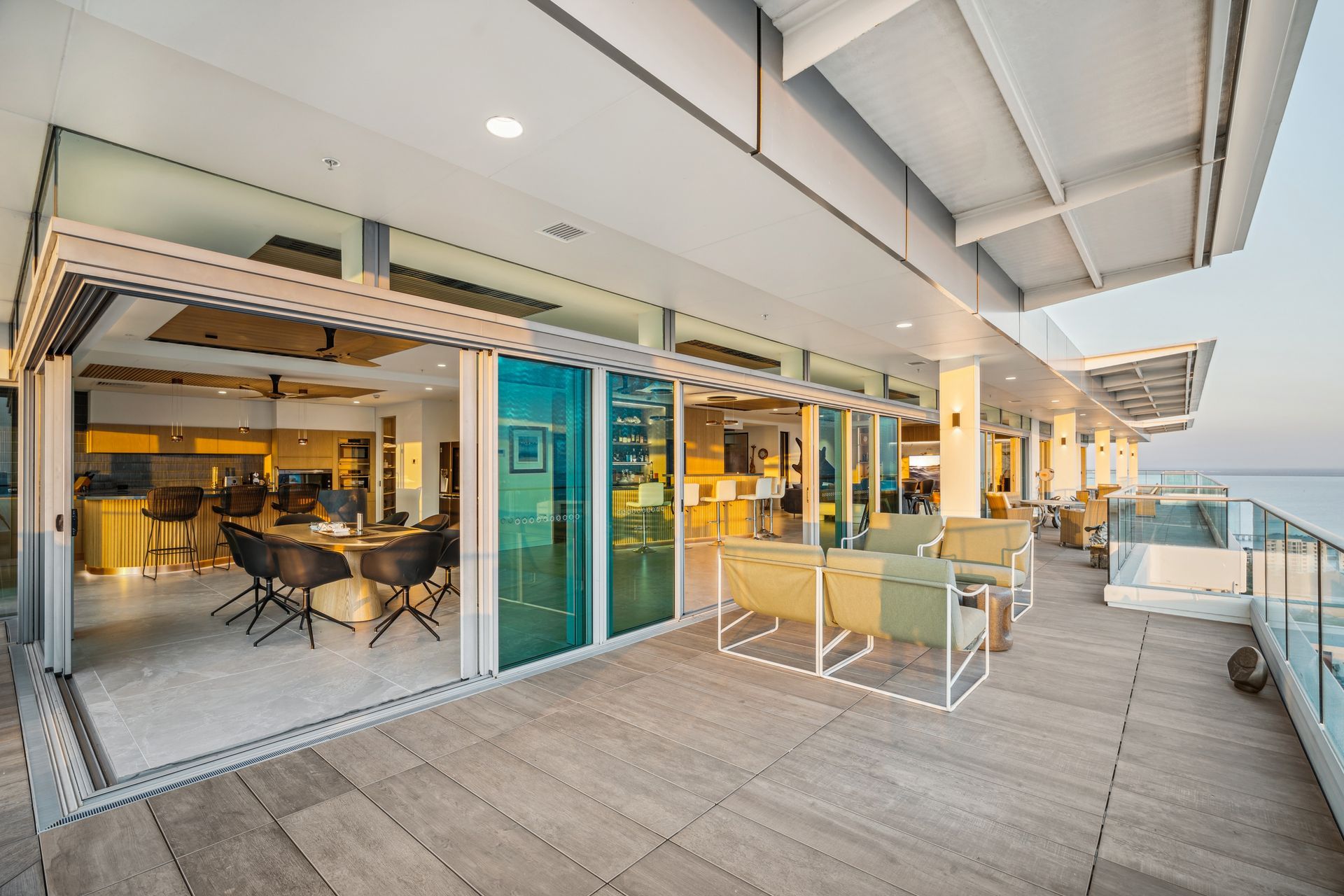 Spacious outdoor patio with ocean view, adjacent to a modern living area with open glass doors.