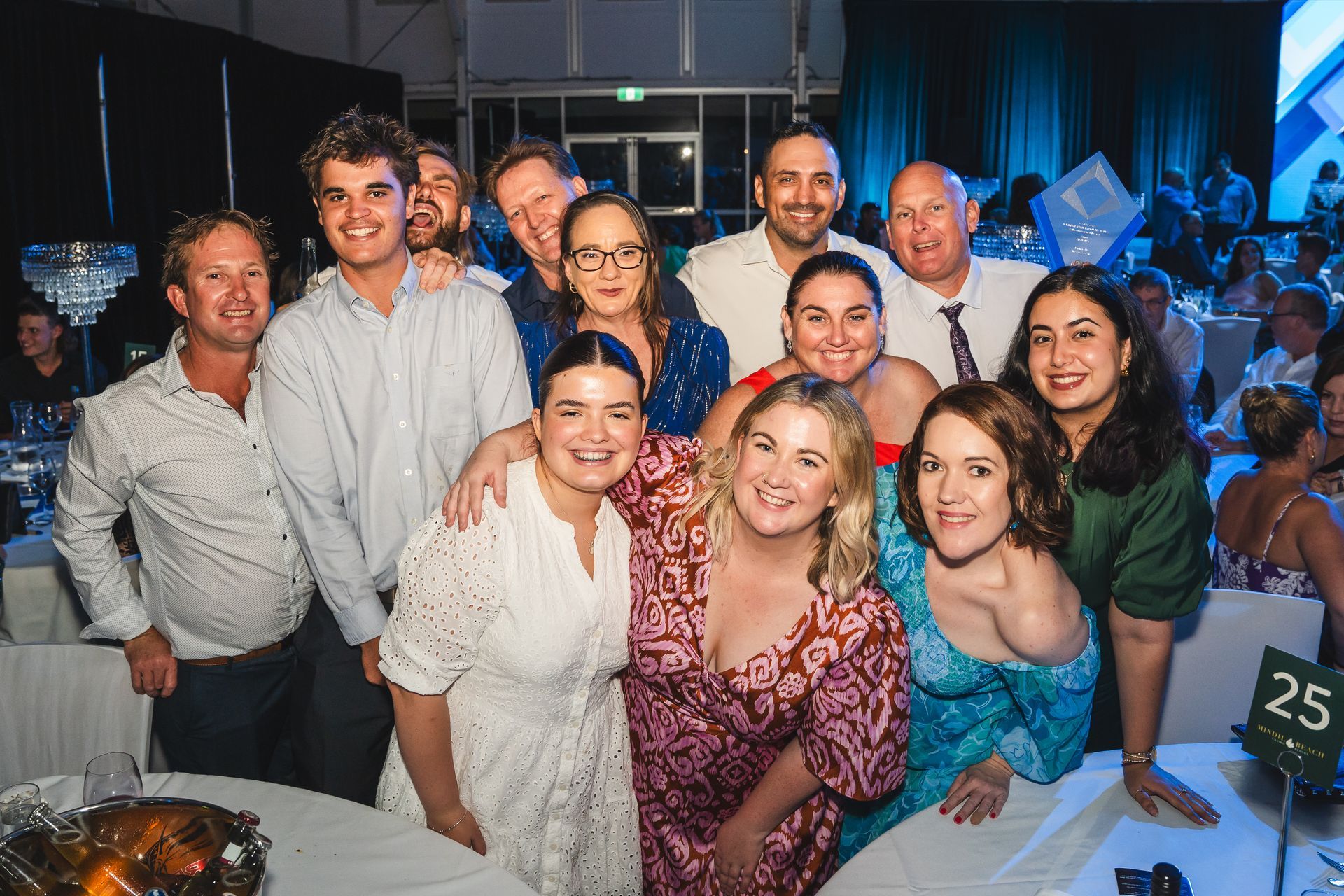 Group of people at an event pose smiling near a table set for a dinner.