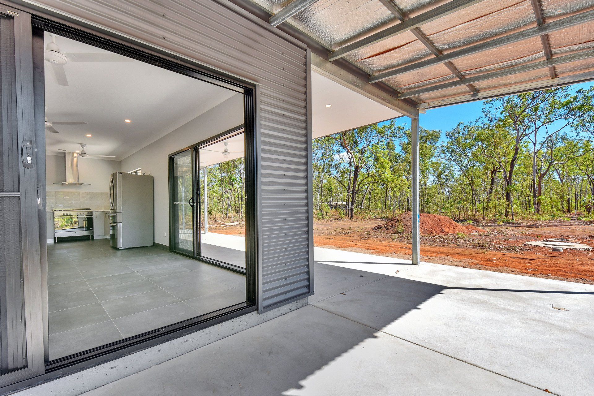 Patio with open sliding doors to an interior kitchen; forest backdrop.
