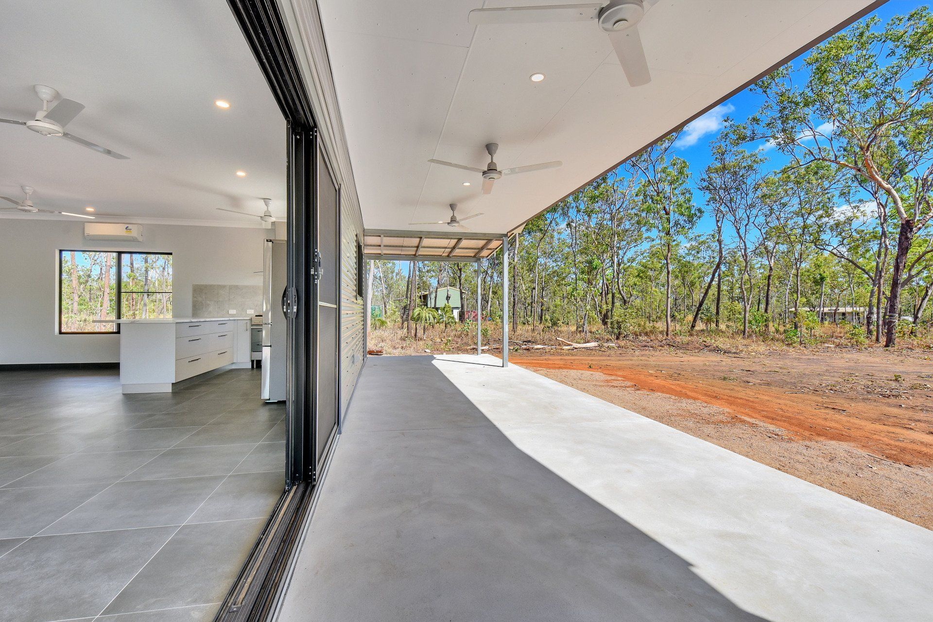 Open-air patio with a view of the forest. Sliding glass door leads to an interior kitchen.