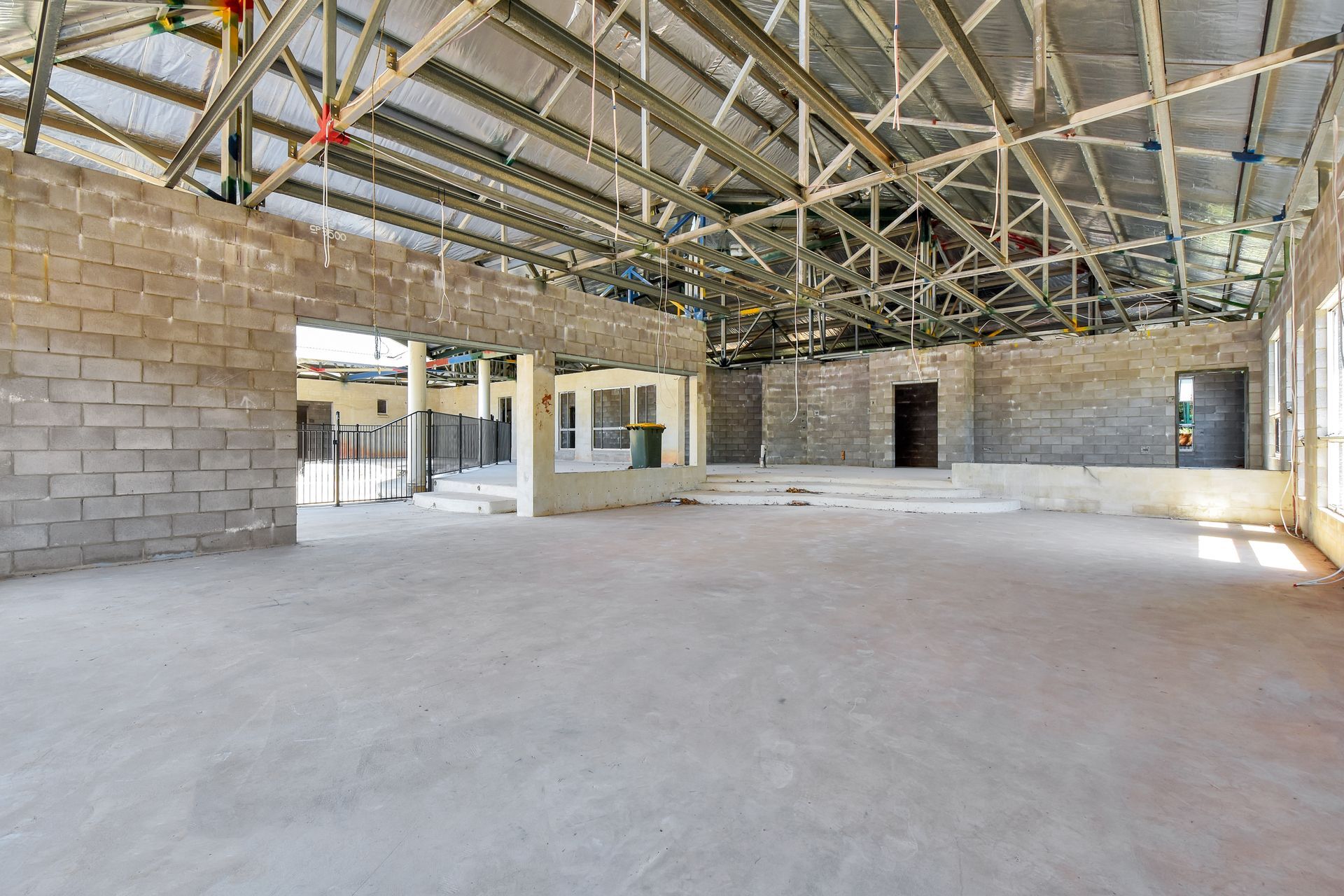 Interior of a building under construction; concrete blocks, exposed ceiling beams, and bare floors.