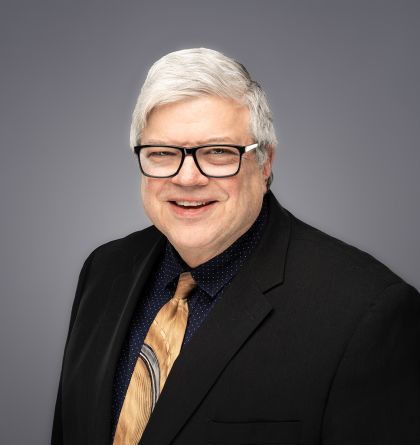 A man in a suit and tie is smiling for the camera.