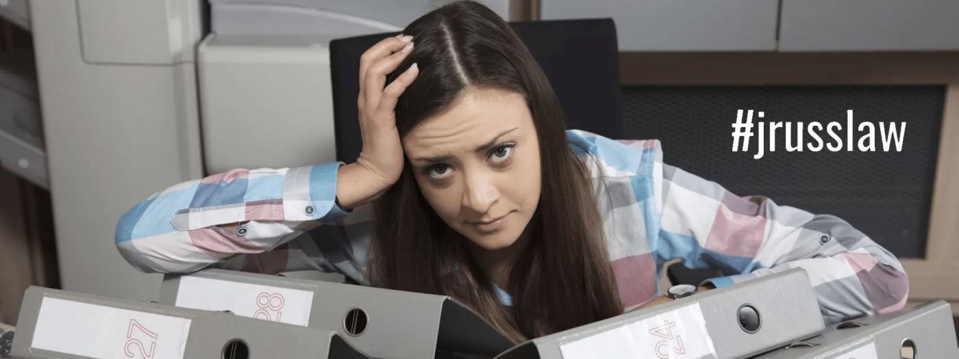 A woman is sitting in front of a pile of binders.