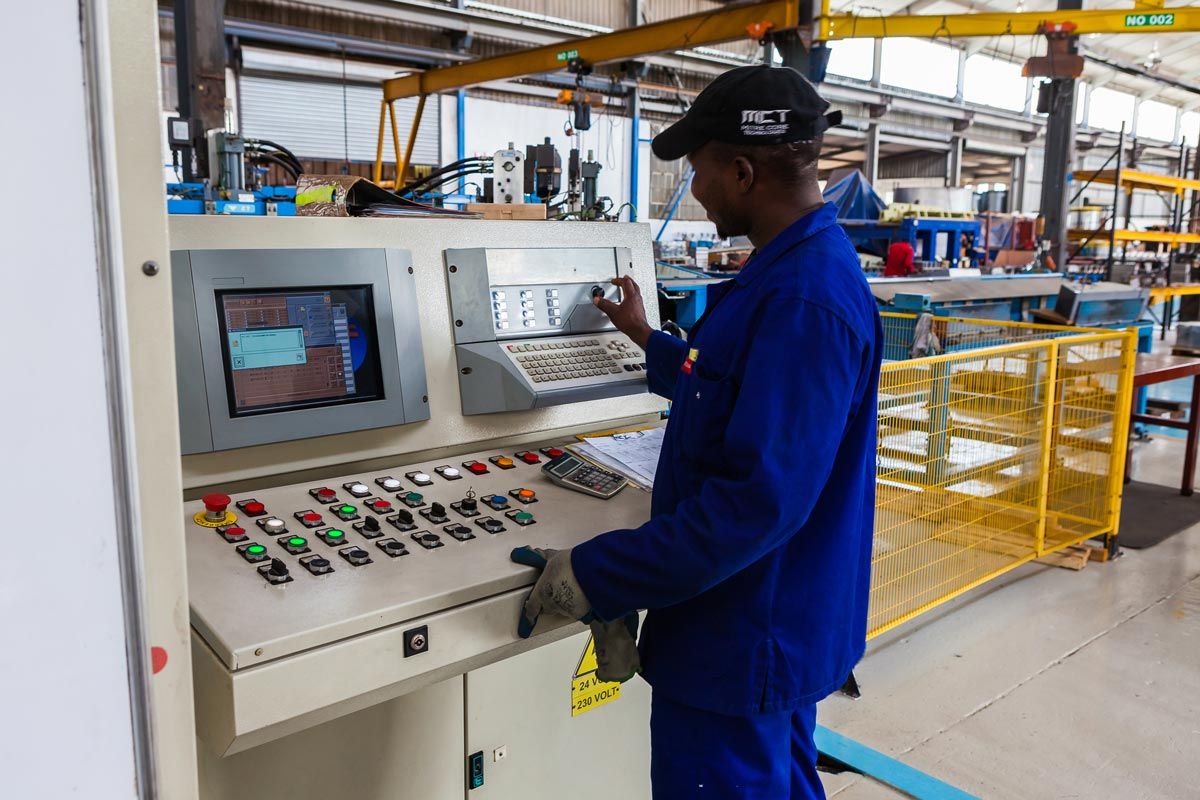 a man is standing in front of a control panel in a factory .