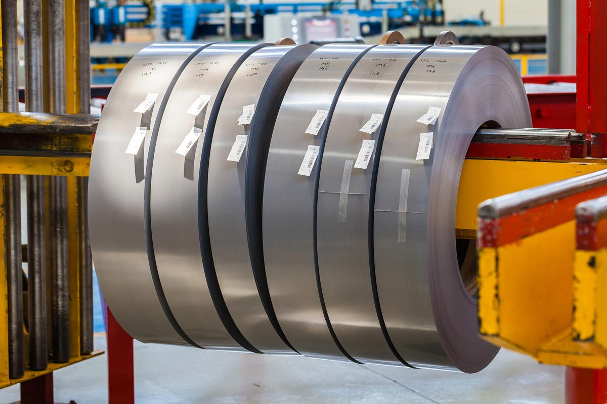 a bunch of rolls of metal are stacked on top of each other in a factory .