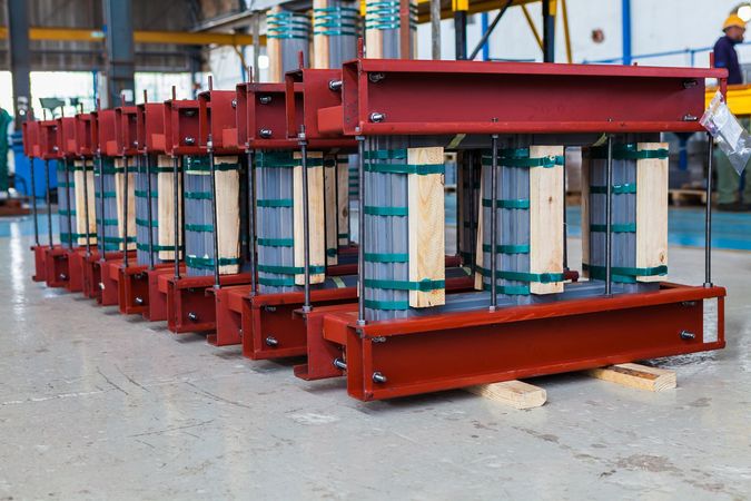 a row of transformers are sitting on a concrete floor in a factory .