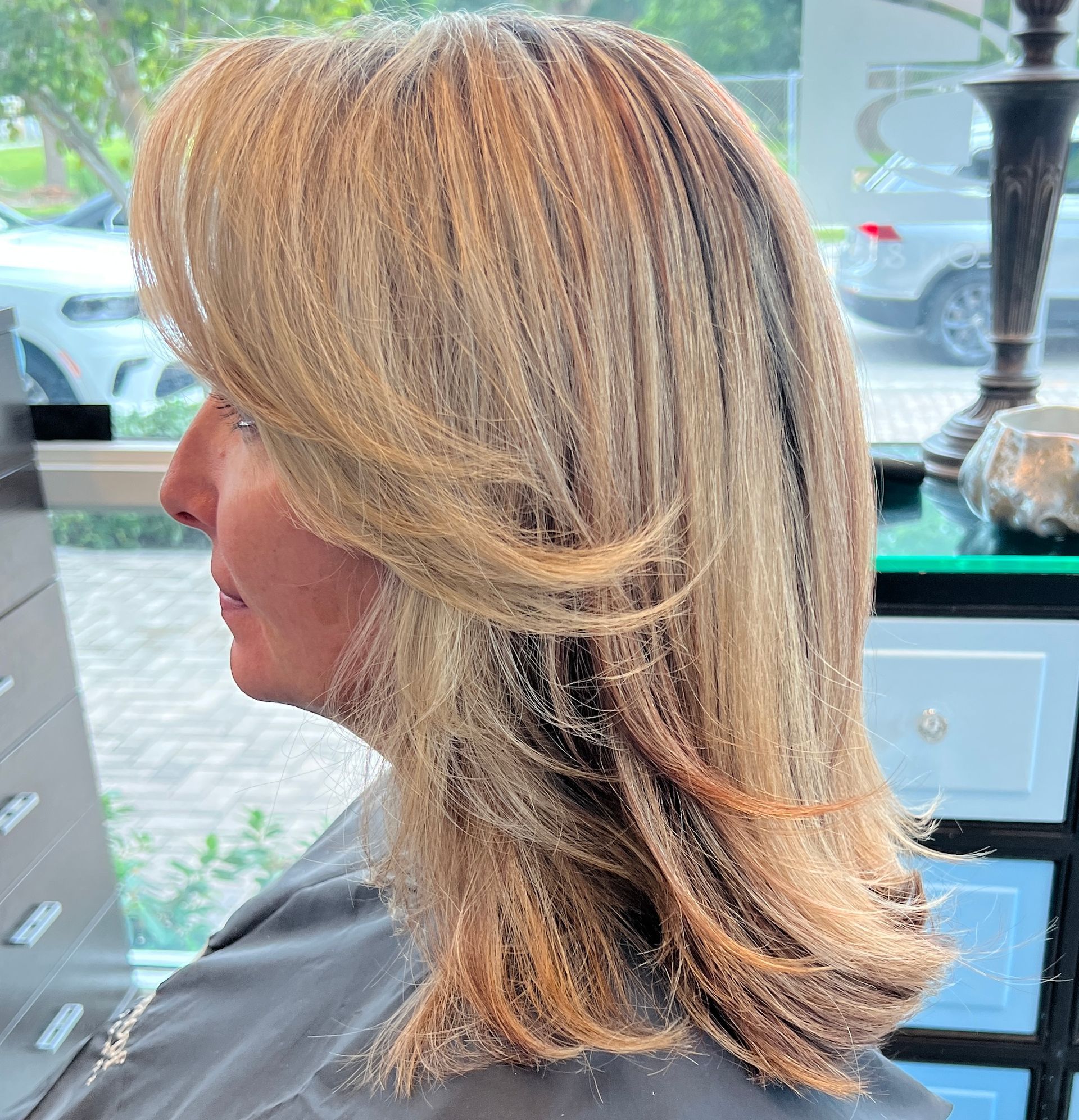 Woman with blonde layered hair; side profile.
