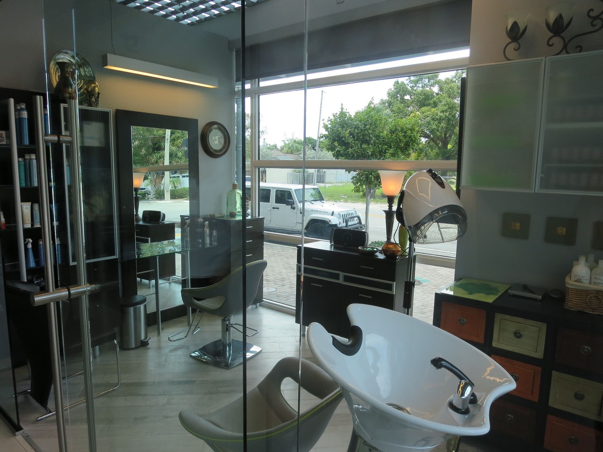 Hair salon interior with styling stations, a sink, and an outside view.