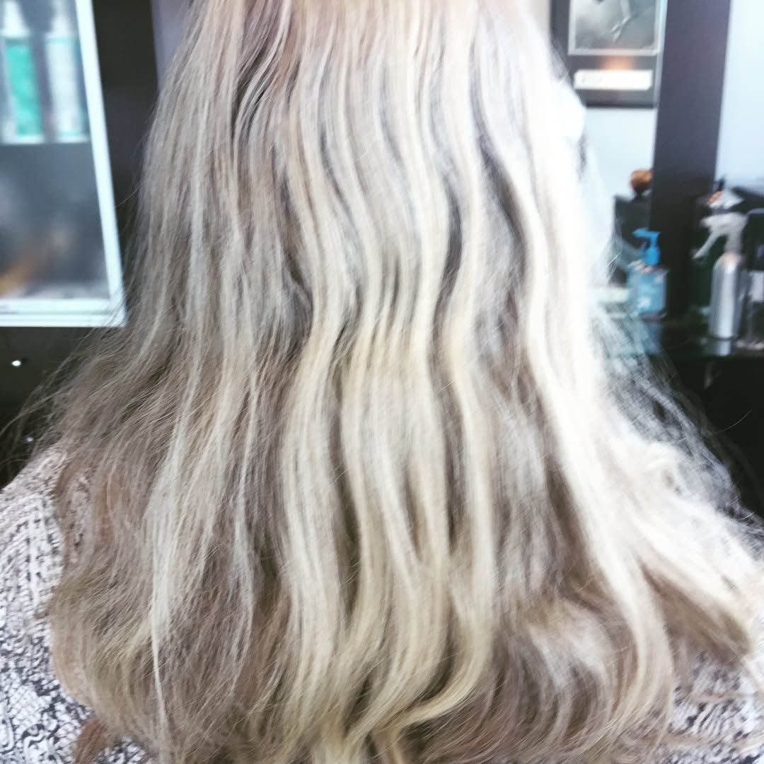 Blonde hair, seen from the back, waves and falls over shoulders.