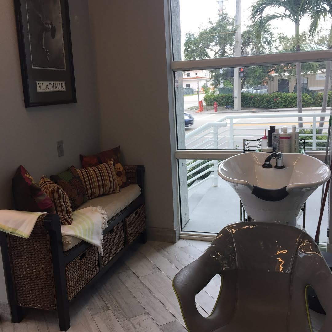 Hair salon with a wash station near a window, seating bench, and a framed picture.