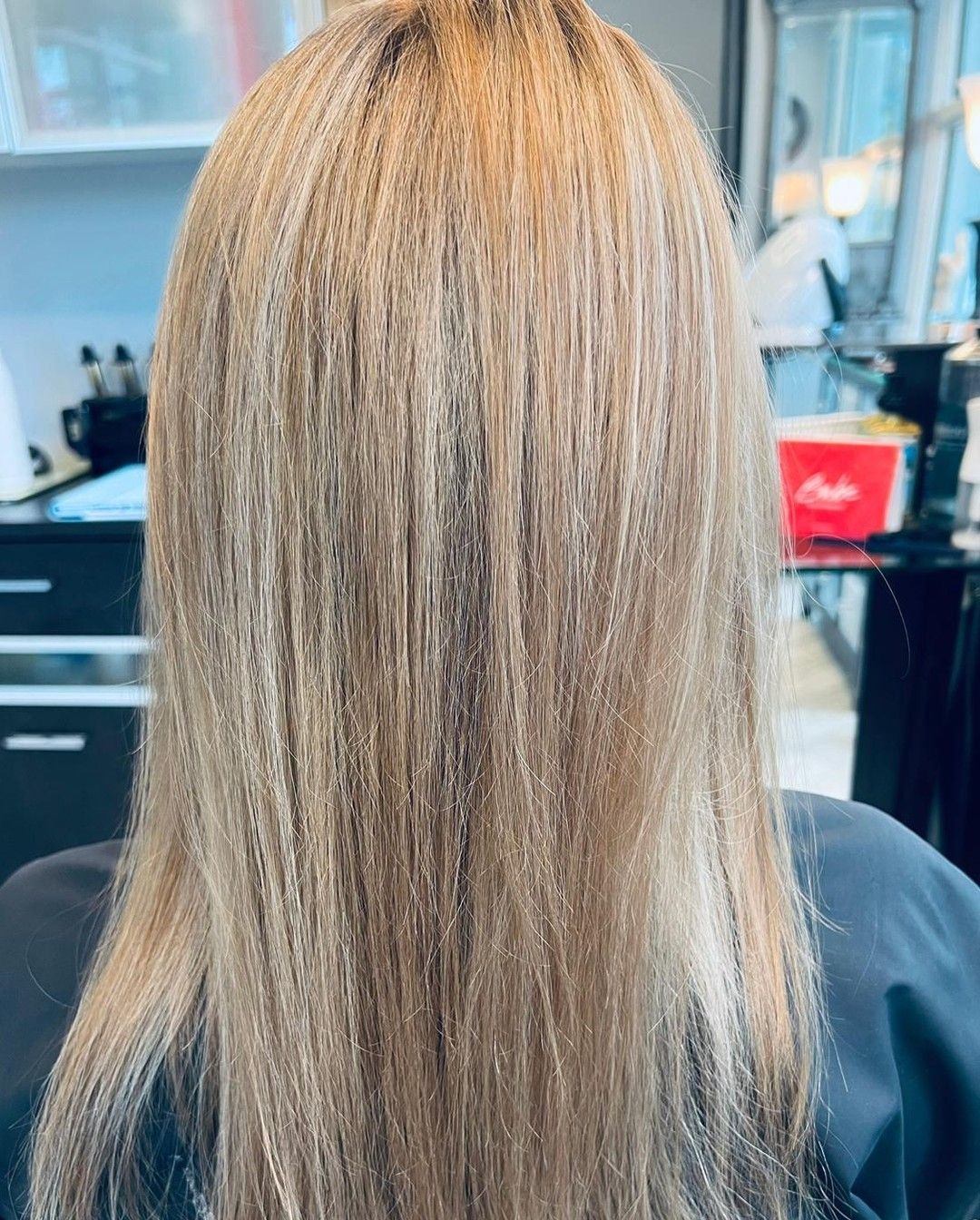 Woman with long, straight blonde hair, in a salon.