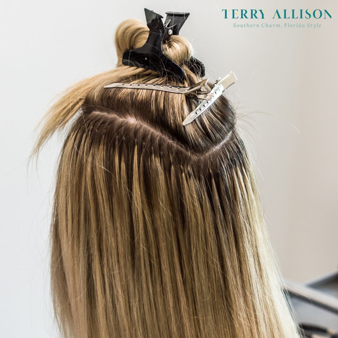 Close-up of blonde hair with dark roots and extensions clipped in with clips.