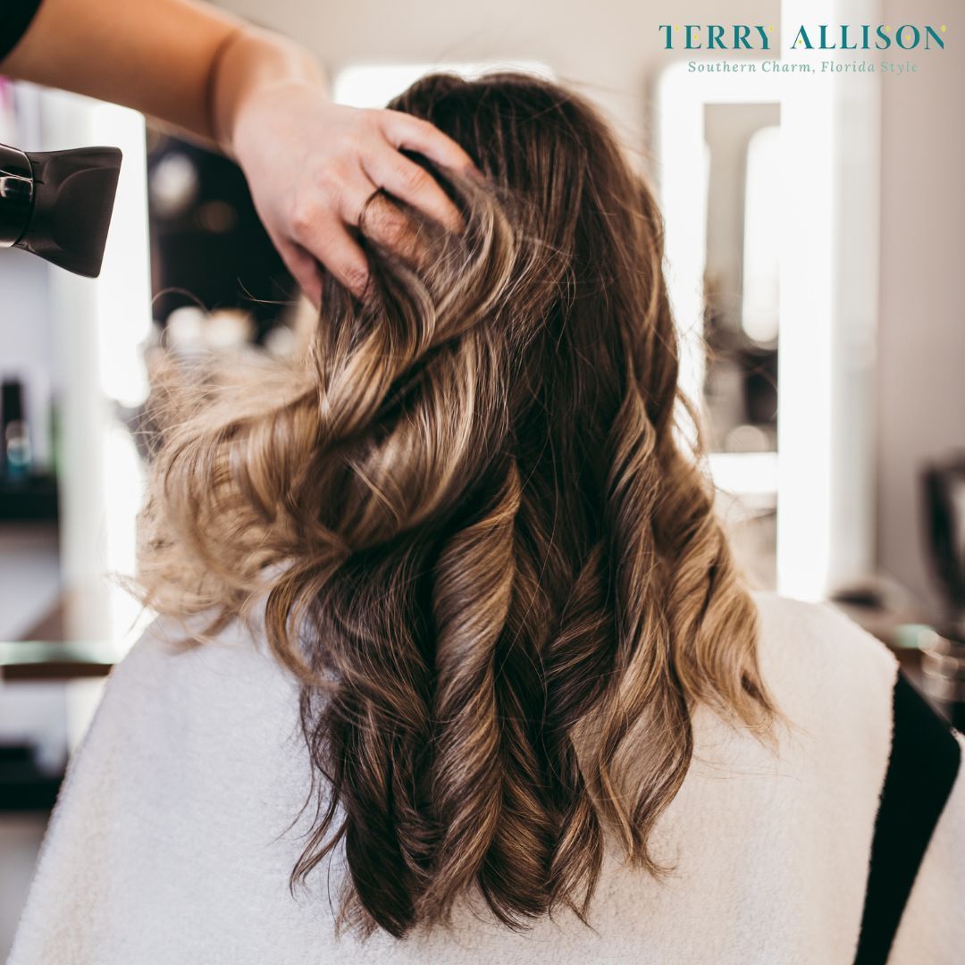 Woman getting hair styled, with a stylist using a hairdryer in a salon.