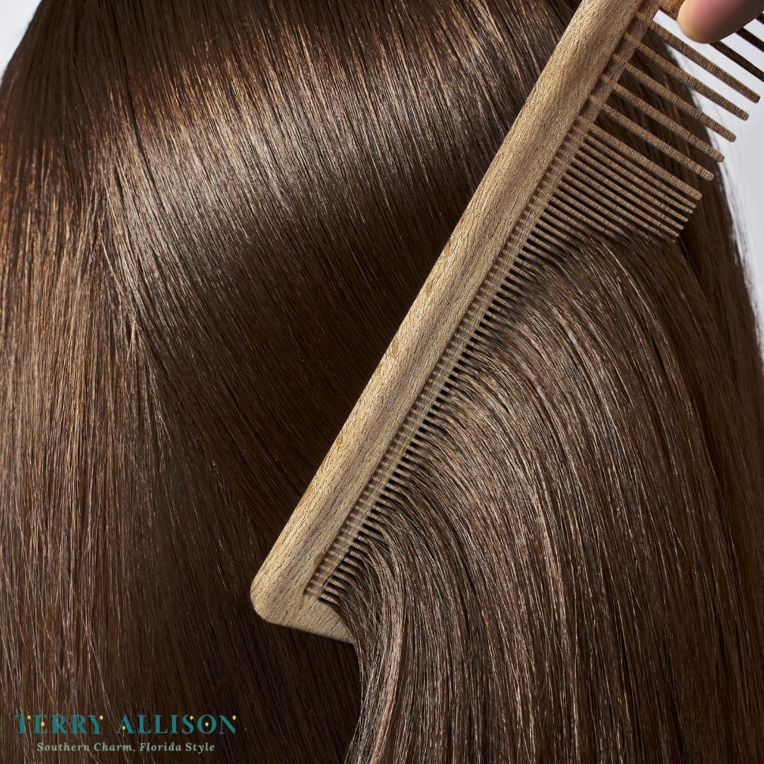 A hand combing shiny, dark brown hair with a light-colored comb.