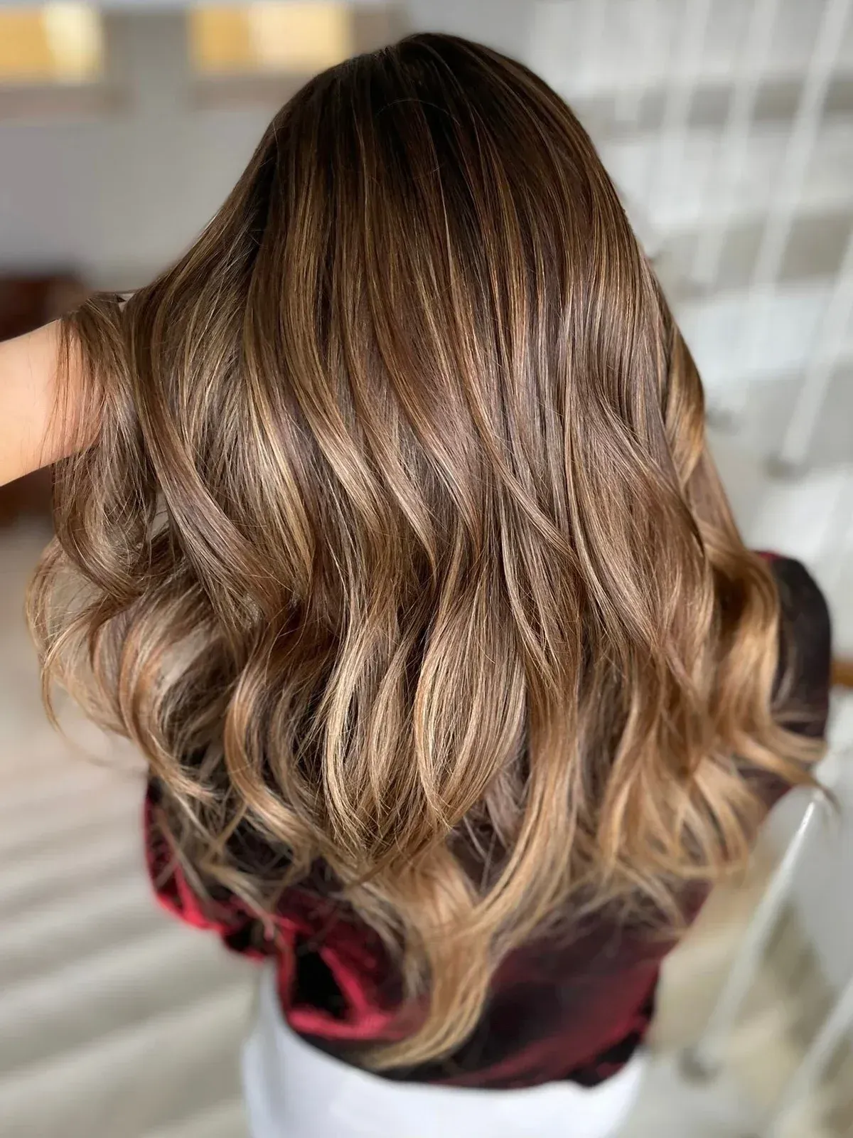 Man in salon with black apron and tattoos stands next to a gray hair chair, inside.
