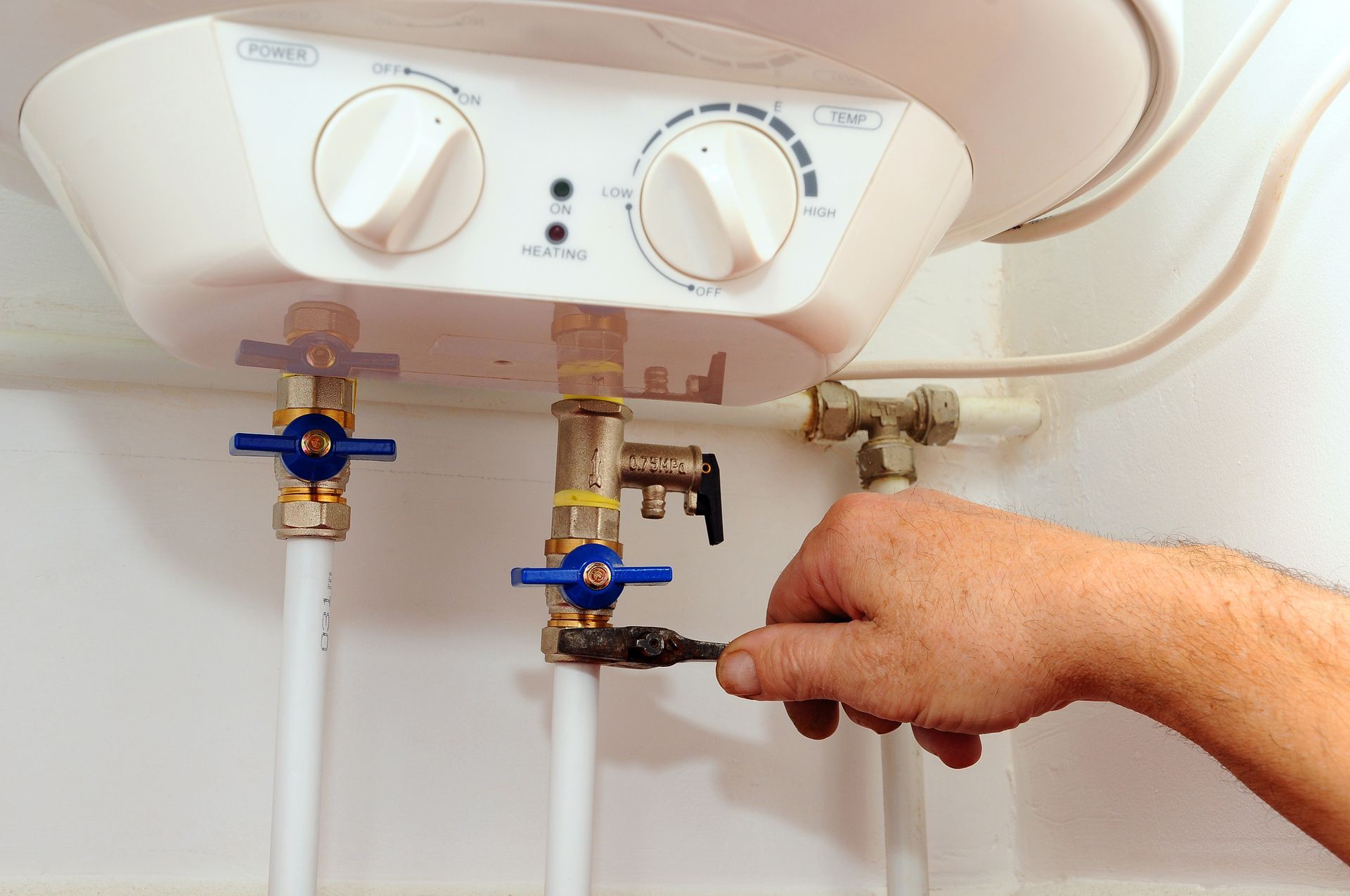 Person adjusting valve connected to a white water heater.