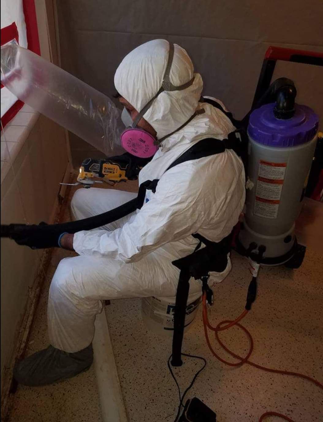 A man in a protective suit is using a vacuum cleaner