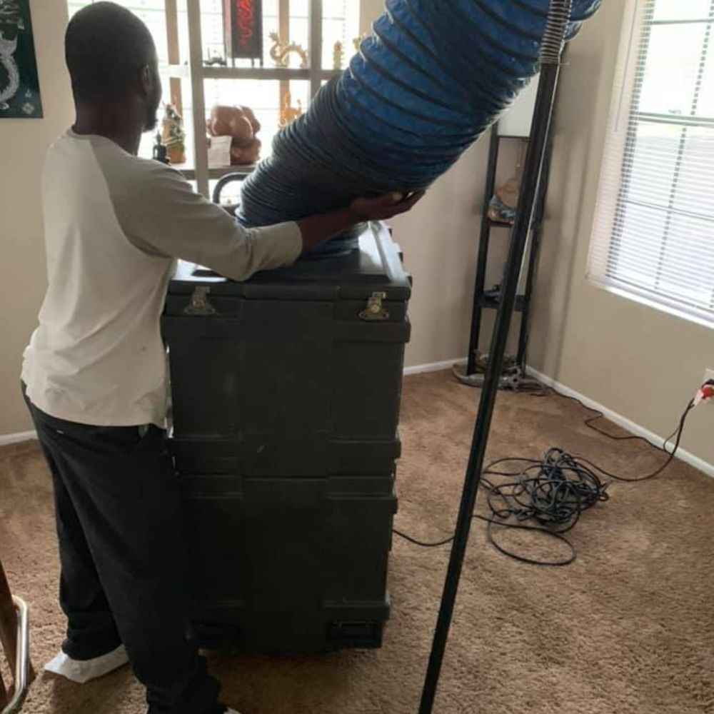 a man is standing in a living room holding a large blue pipe .