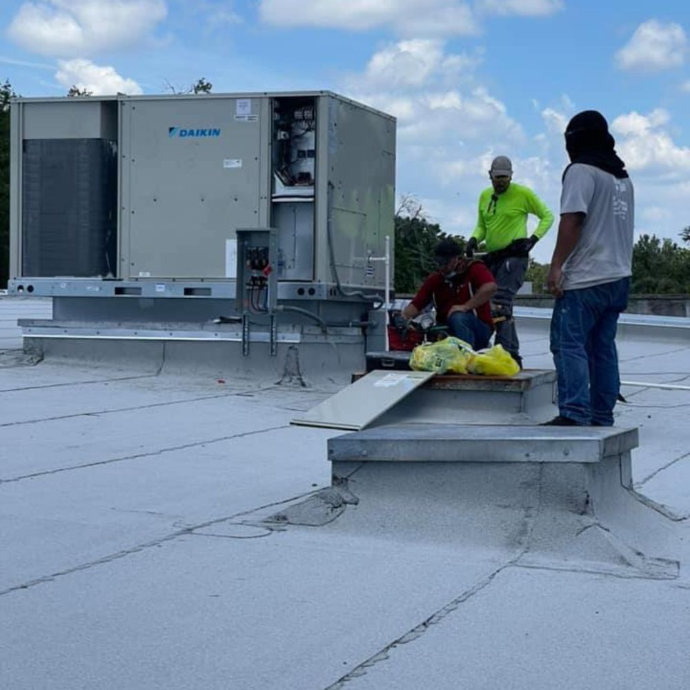 a group of people are working on a roof with a daikin air conditioner in the background