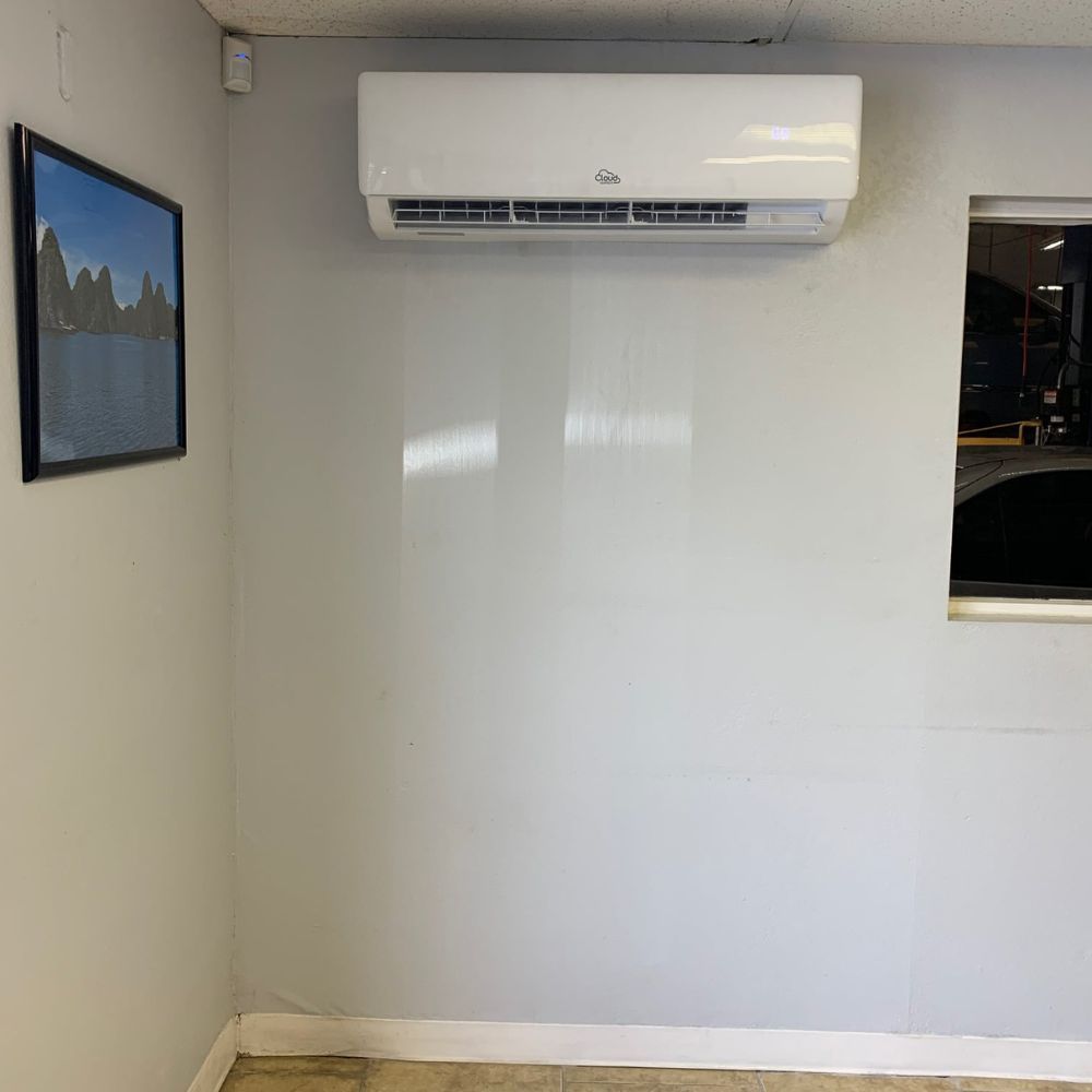 a room with a wall mounted air conditioner and a picture on the wall .