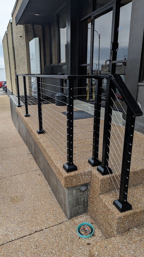 A black railing on a sidewalk next to a building.