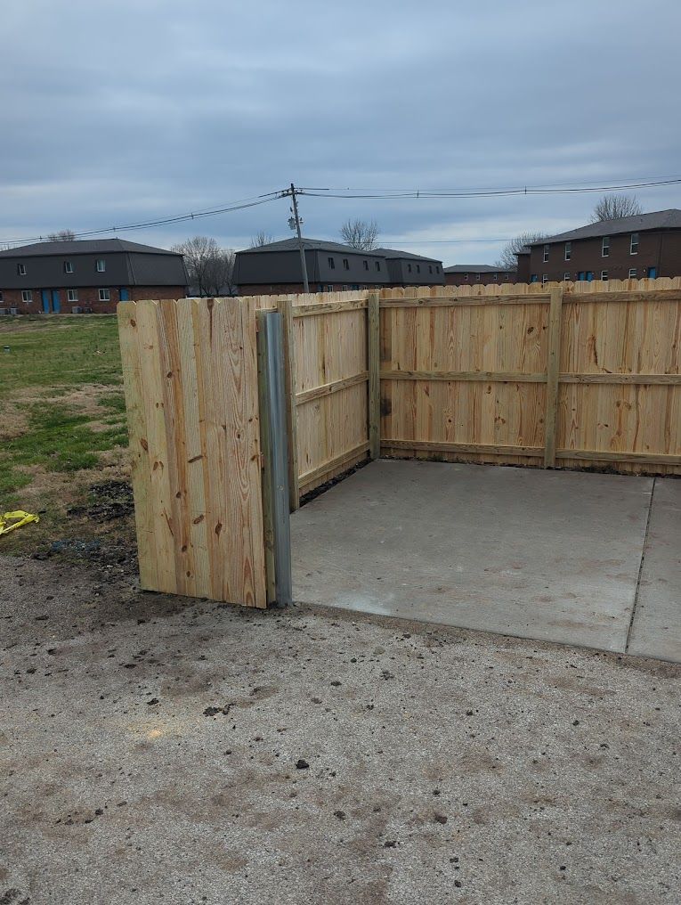 A wooden fence is surrounding a concrete area.
