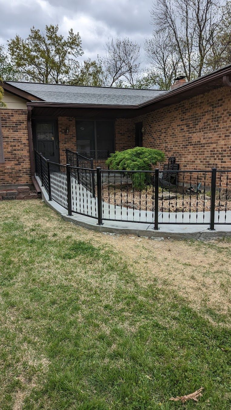 Brick house with a ramp leading to the entrance, black railings, and white vertical accents on the sides.
