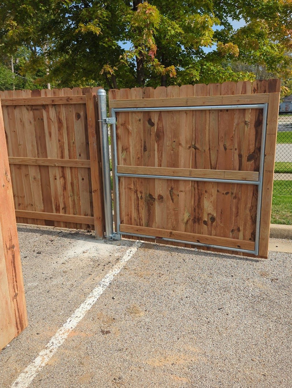 A wooden fence with a gate in a parking lot.