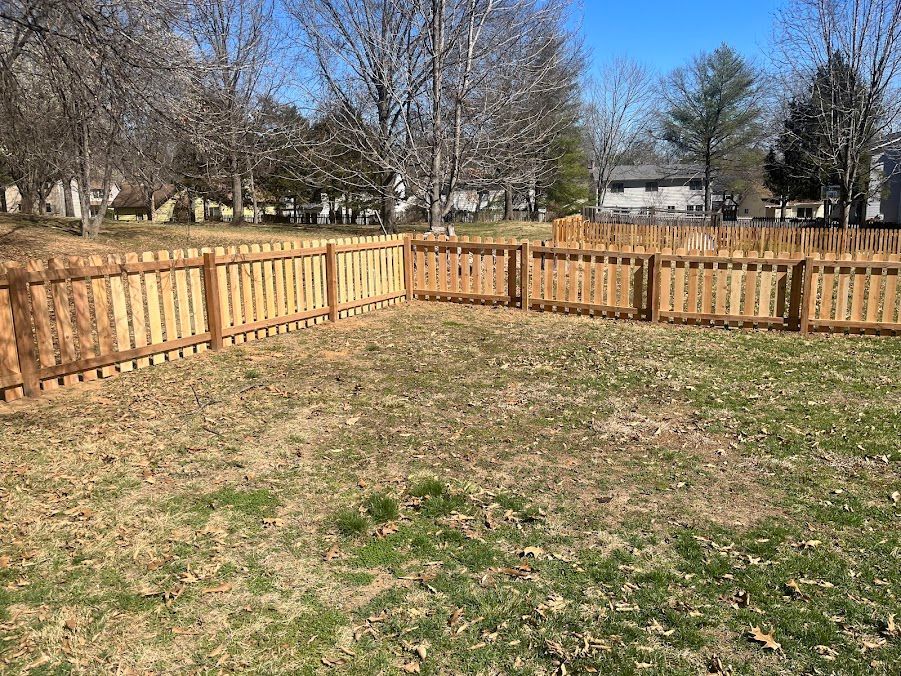There is a wooden fence in the middle of a grassy field.